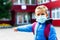 Attractive schoolboy in protective mask standing outdoor excited child points finger at school close up