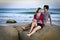 Attractive seaside couple sitting on rock at twili