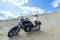 Attractive sensual woman lies on motorcycle among the sands