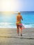 Attractive sexy young woman walks on the beach in a bikini and colorful pareo, luxurious summer vacation, vertical shot, sun rays