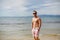 Attractive shirtless athletic young man on the beach by the sea. Young muscular man with perfect body in shorts and