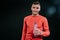 Attractive shot portrait of handsome smiling muscular Caucasian man wearing red sportswear with bottle of water, relaxing after in