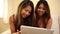 Attractive sisters sitting on couch using tablet