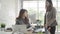 Attractive smart Asian business woman in smart casual wear working on laptop while sitting on desk while her angry manager.