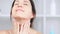 Attractive smiling adult woman applying anti-aging cream on neck and contour of chin close-up