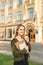 Attractive smiling caucasian young female student with students books holding take away coffee in front of university. College