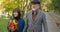 Attractive smiling elderly couple bearded husband and wife with a bouquet of autumn leaves enjoy an active walk in the
