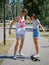 An attractive smiling fellow teaching a girl riding on a longboard in a park on a natural blurred background.