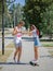 An attractive smiling fellow teaching a girl riding on a longboard in a park on a natural blurred background.