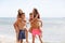 Attractive smiling fellows holds beautiful girls on a seashore on a natural blurred background.