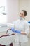 Attractive smiling female doctor in a white uniform at the workplace. Young beautiful female dentist in mask and gloves