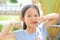 Attractive smiling little child girl touching nose with thumb with expression happy and relax outdoor. Portrait Asian kid in