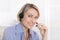 Attractive smiling middle aged woman in blue calling with headset.