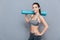 Attractive smiling sportswoman holding yoga mat