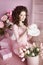 Attractive smiling teen girl portrait open present, romantic surprise. Brunette in pink dress over bouquet of flowers and gift bo