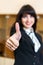 Attractive smiling woman in office shows thumb up