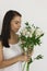 Attractive smiling young woman create Bouquet of white flowers