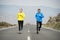 Attractive sport couple man and woman running together on asphalt road mountain landscape