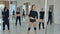 Attractive sport girls stretching before pole dance class in gym with windows