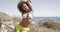 Attractive sportive woman with curls posing at camera flirty while sitting on fence