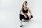 attractive sportswoman in black sportswear sitting on floor