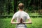 Attractive sporty man doing yoga outdoors in the park. Holding Anjali Mudra behind the back, exercise for flexibility in the hands