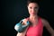 Attractive sporty woman with short hair ready to press kettle bell with her right hand. Woman athlete in indoor sportswear agains