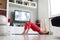 Attractive sporty woman working out at home, doing pilates exercise in front of television in her small studio