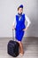 Attractive stewardess in blue uniform and cap with suitcase