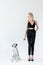 attractive stylish blonde woman in black clothes holding dalmatian dog leash