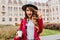 Attractive stylish girl posing with gently smile and holding cup of coffee in morning. Outdoor shot of pleasant