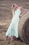 Attractive stylish Woman in long white summe dress near hay bal