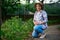 Attractive successful woman, ecological farm owner , sits next to tomato seedlings and smiles sweetly, looking at camera