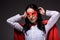 attractive super businesswoman in red cape tying mask