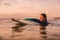 Attractive surf girl with perfect body on surfboard in ocean. Surfing at sunset