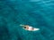 Attractive surf girl relaxing on surfboard in transparent ocean. Aerial view with surf woman