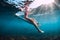 Attractive surfer girl sit at surfboard underwater in ocean