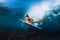 Attractive surfer woman dive underwater with under wave.