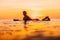 Attractive surfer woman on a surfboard in ocean. Surfgirl at sunset