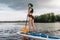 attractive tattooed woman with blue hair standup paddleboarding