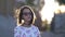 Attractive teen brunette girl in glasses looking at the camera at sunset in windy weather