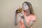 Attractive teen girl stands against the orange wall in an orange T-shirt and holds a big burger in her hand, she opens her mouth