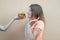 Attractive teen girl stands against the orange wall in an orange T-shirt and sniffs a big burger, the other hand gives a