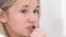 An attractive teenage girl brushes her teeth carefully in front of the bathroom mirror.