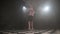 Attractive teenage girl dancing solo ballroom sport dancing latino in a dark studio room filled with smoke. Professional