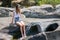 Attractive teenage girl sitting on rock ledge with legs splashing cool water