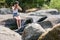 Attractive teenage girl sitting on rock ledge with legs splashing cool water