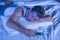 Attractive tired man in bed falling asleep while using mobile phone still holding the cellular in his hand while sleeping in inter