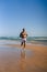 An attractive topless man with tattoos running on a beach next to a sea