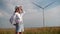 Attractive tourist walking near a field with alternative green energy windmills